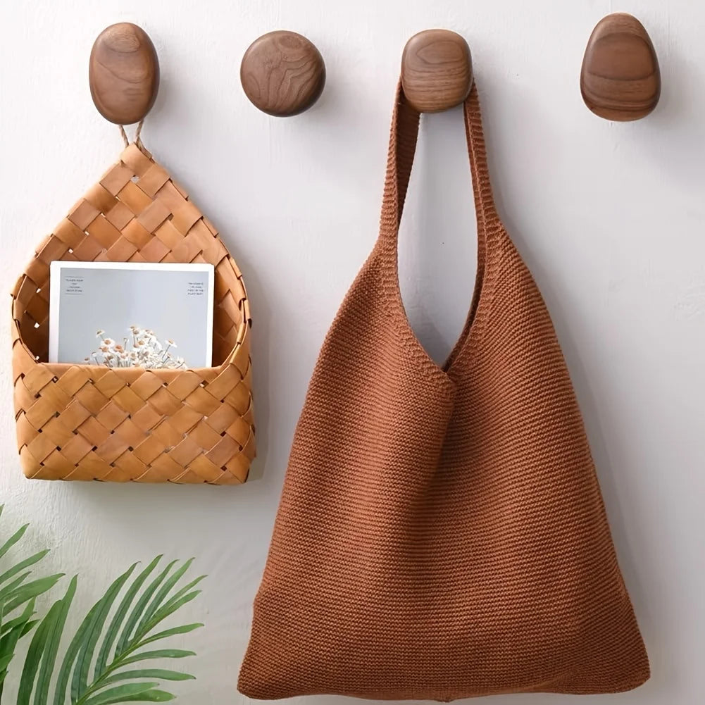 Patères rondes en noyer fixées au mur avec un sac en tricot et un panier tressé suspendus