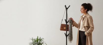 Femme accrochant une écharpe et un sac sur un porte-vêtements noir en forme de branche
